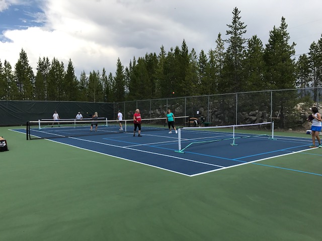 A group of people playing tennis on a court.
