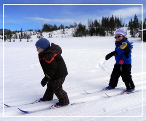 Two children are skiing on a snowy slope.