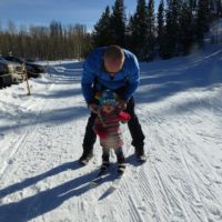 A man and child on skis in the snow.