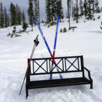 A bench with skis on it in the snow.