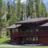 A large red house with a porch and trees in the background.