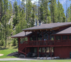 A large red house with a porch and trees in the background.