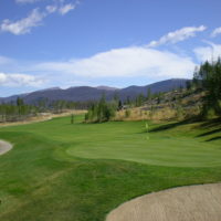 A golf course with trees and mountains in the background.