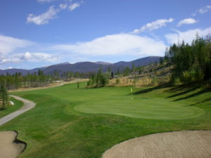 A golf course with trees and mountains in the background.