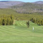 A golf course with trees and mountains in the background.