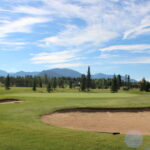 A golf course with trees and mountains in the background.