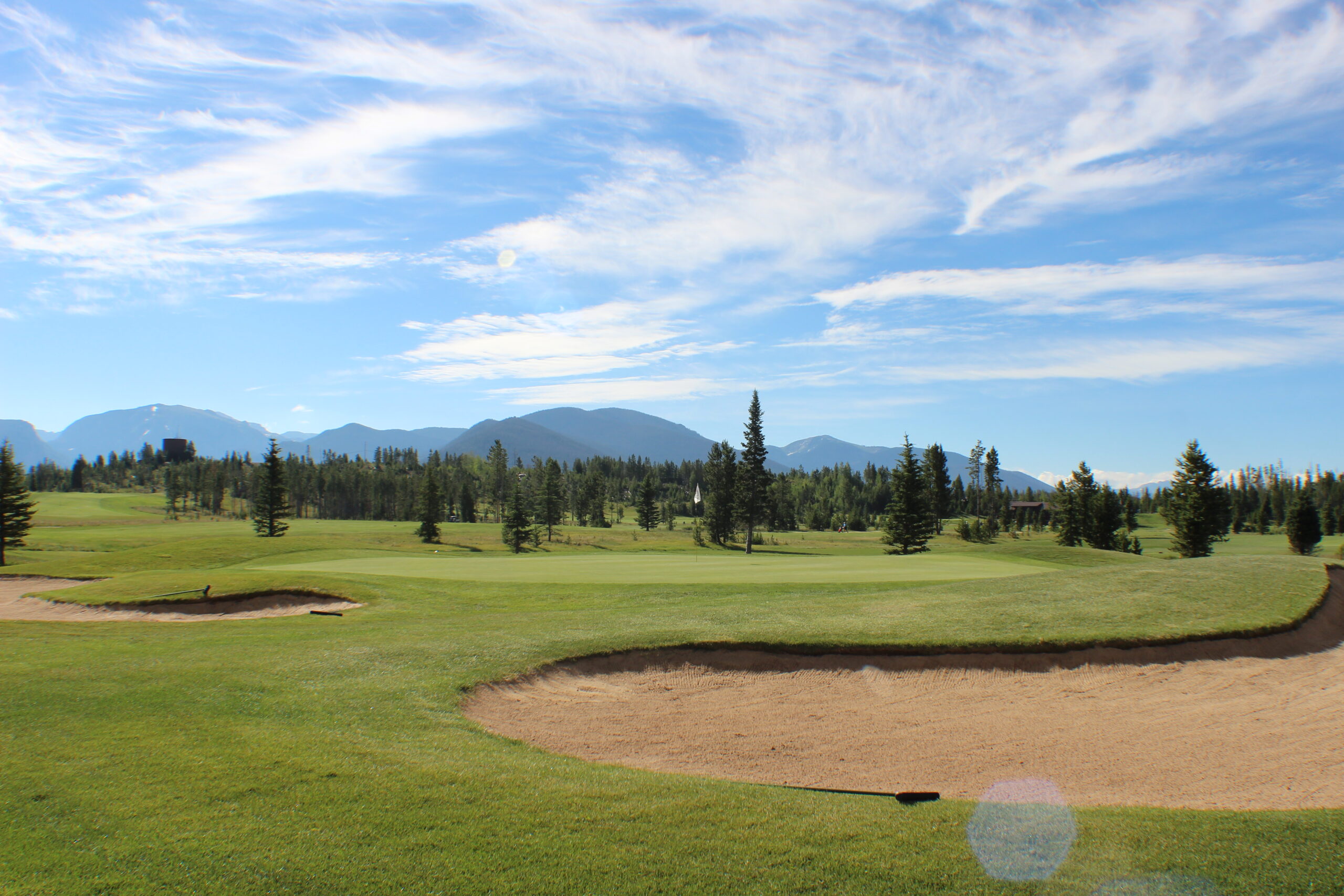 Golf green with bunkers and distant mountains